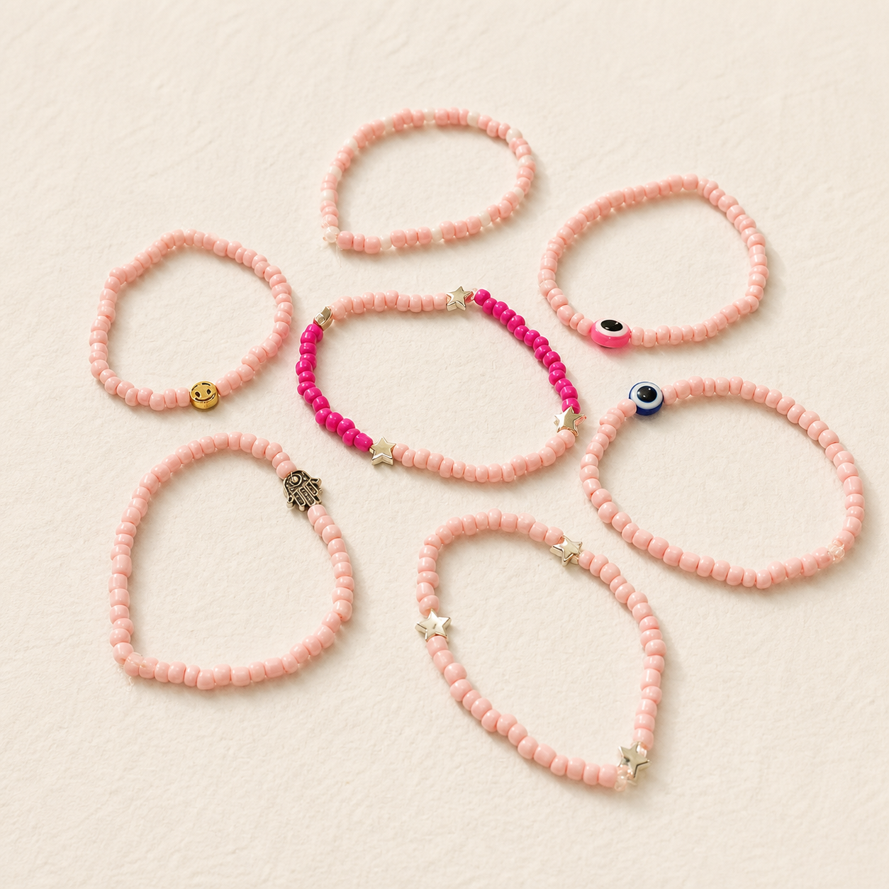 Pulseras rosas con dijes de ojo, estrella y mano