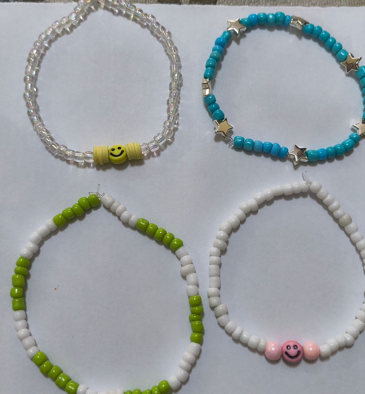 Cuatro pulseras artesanales de colores con cuentas y dijes